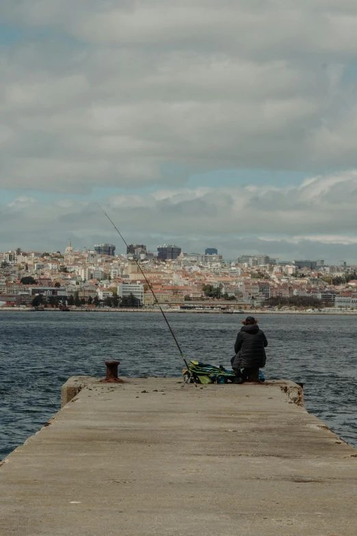 the person is fishing off a pier on the lake