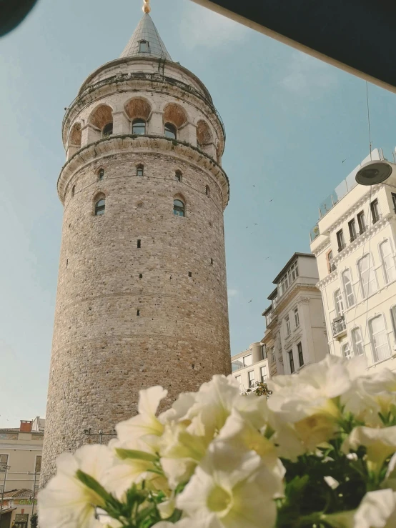 a small tower on the side of a building with flowers in front