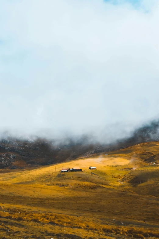 a brown hills covered in clouds and green grass