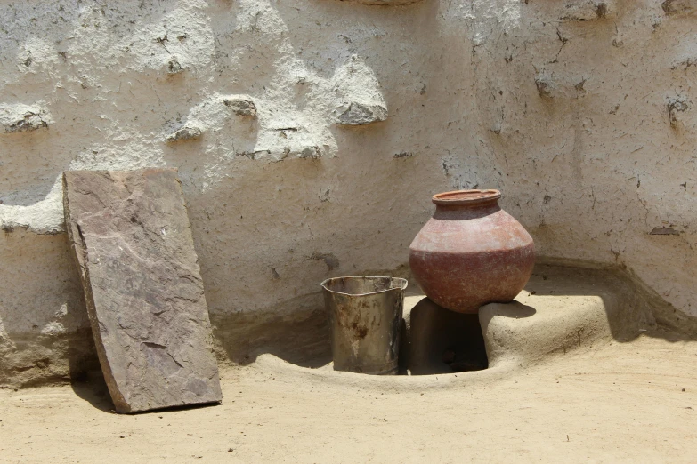 vases sit against a wall that is covered in sand