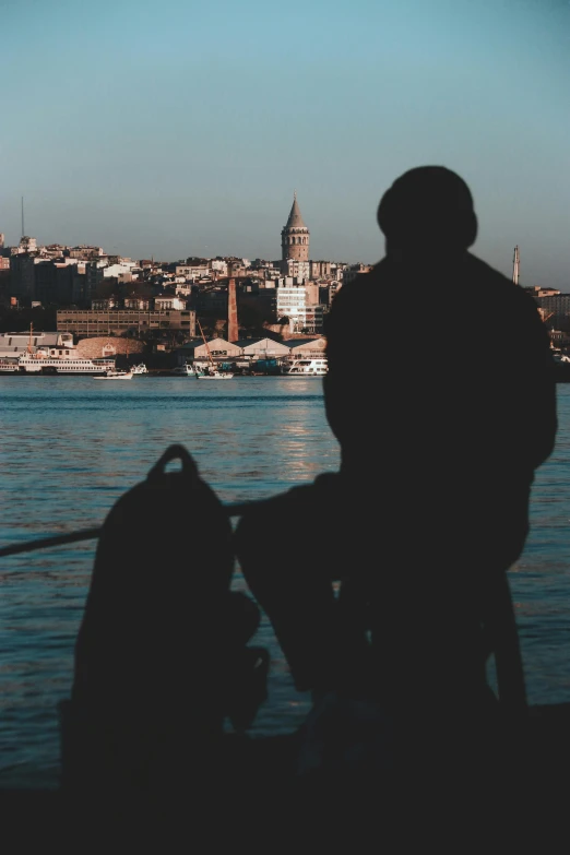 a person that is sitting on the pier looking at the water