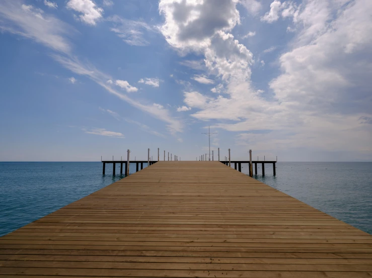 a pier is surrounded by blue ocean water and cloudy skies