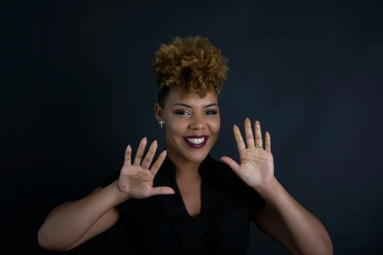 a woman with glitter hands smiles and poses for the camera