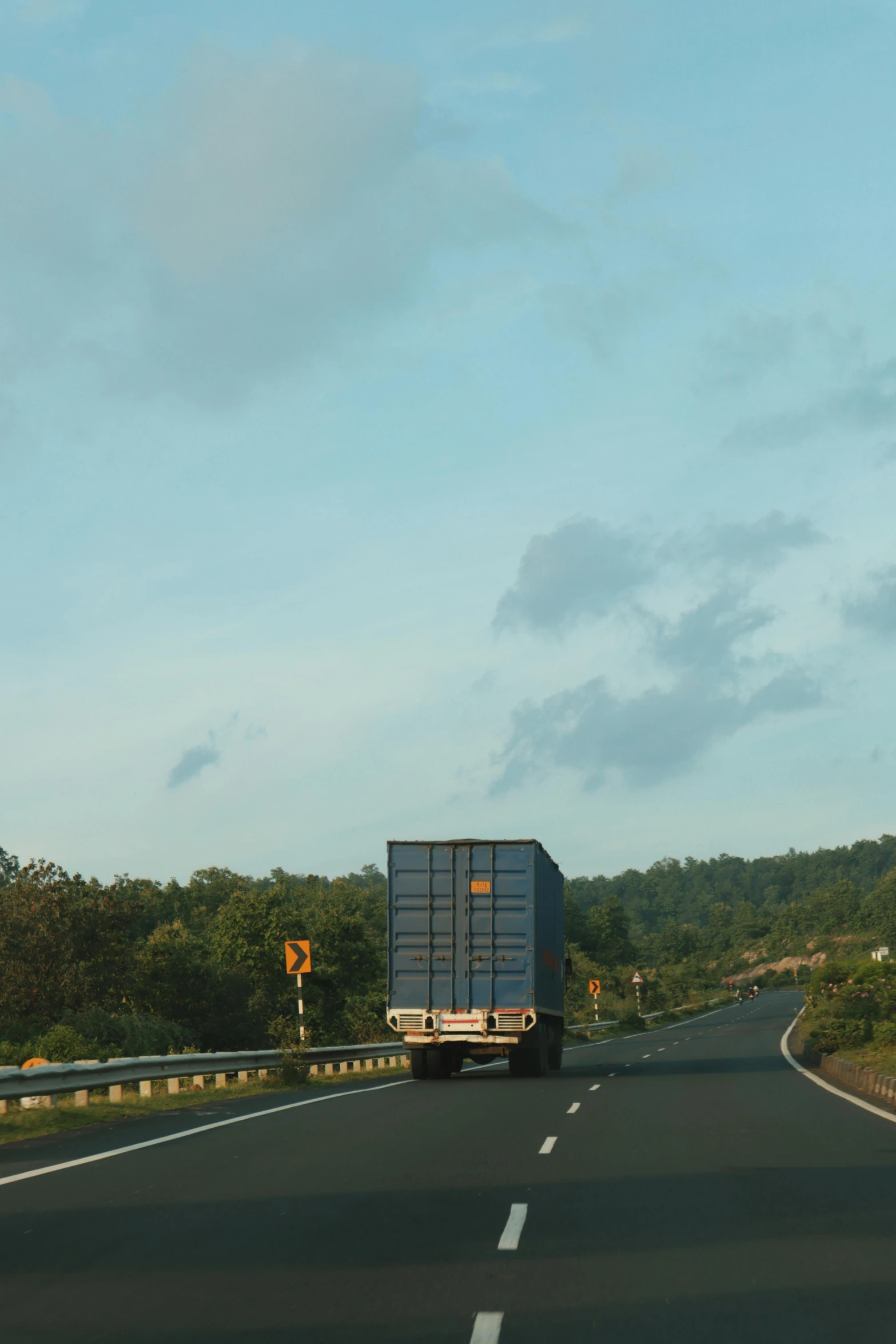 a truck driving on the highway, with trees in the background