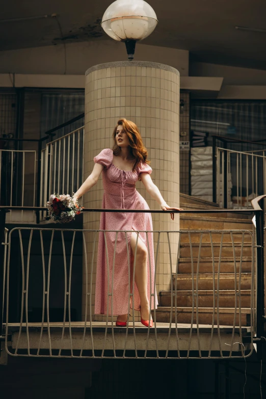 a woman wearing a dress standing on a rail