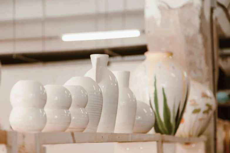 a lot of white vases that are on a shelf