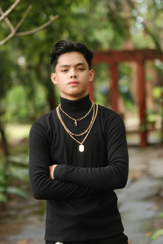 a male in a black shirt with a chain around his neck