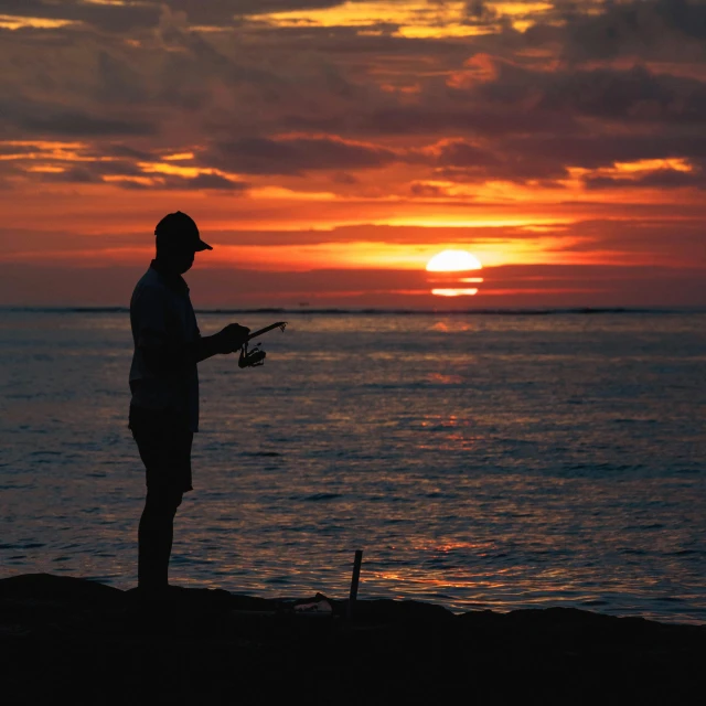 man standing on the beach looking out at the sun