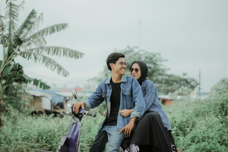 a couple is sitting on a motorcycle in a field