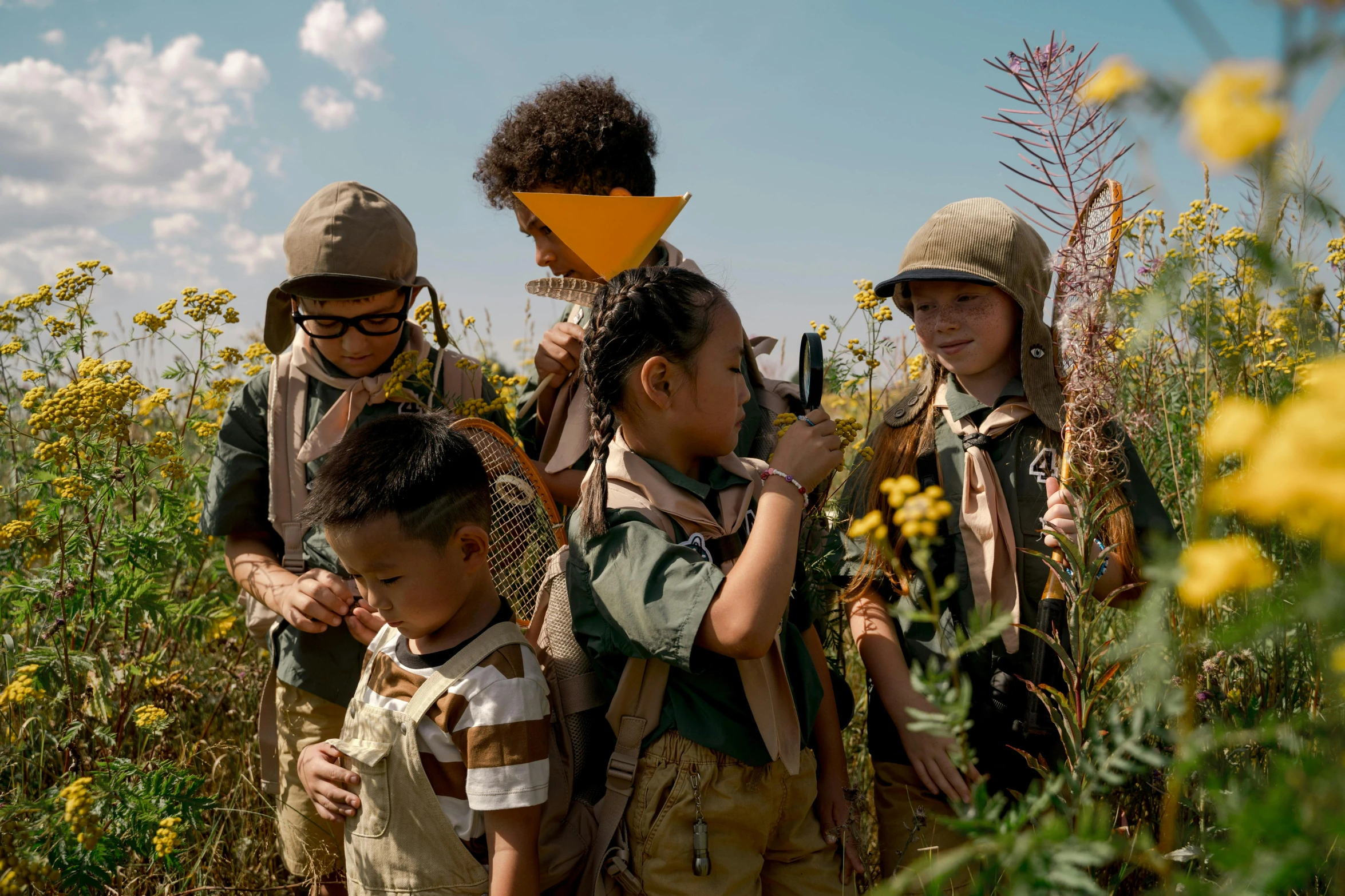 some children with backpacks standing together in a field of flowers