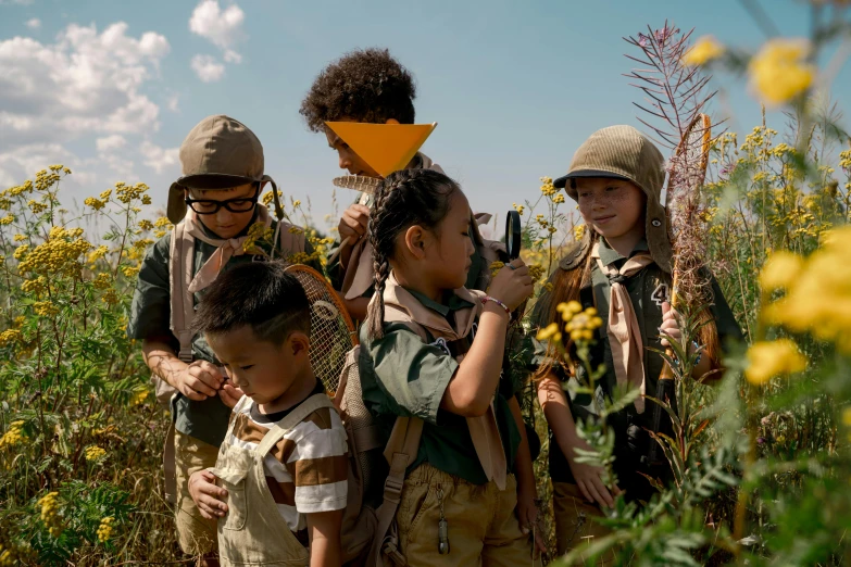 some children with backpacks standing together in a field of flowers