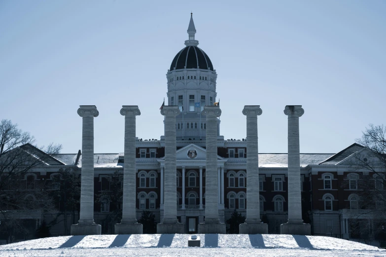 the top of a building with large pillars and a clock