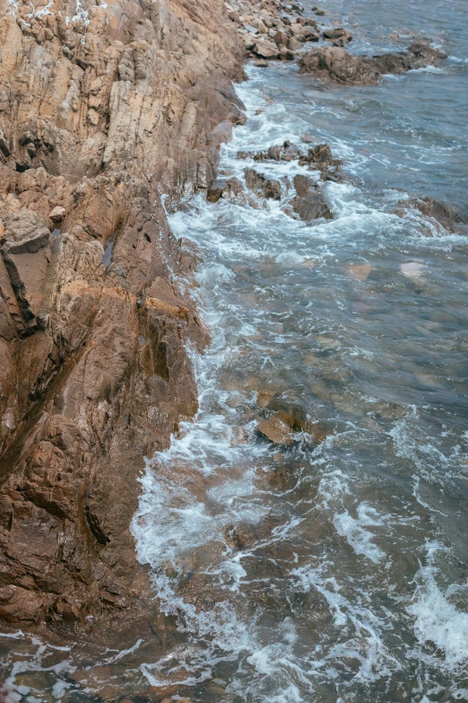 sea sprays from the rocks as they are broken by the wind