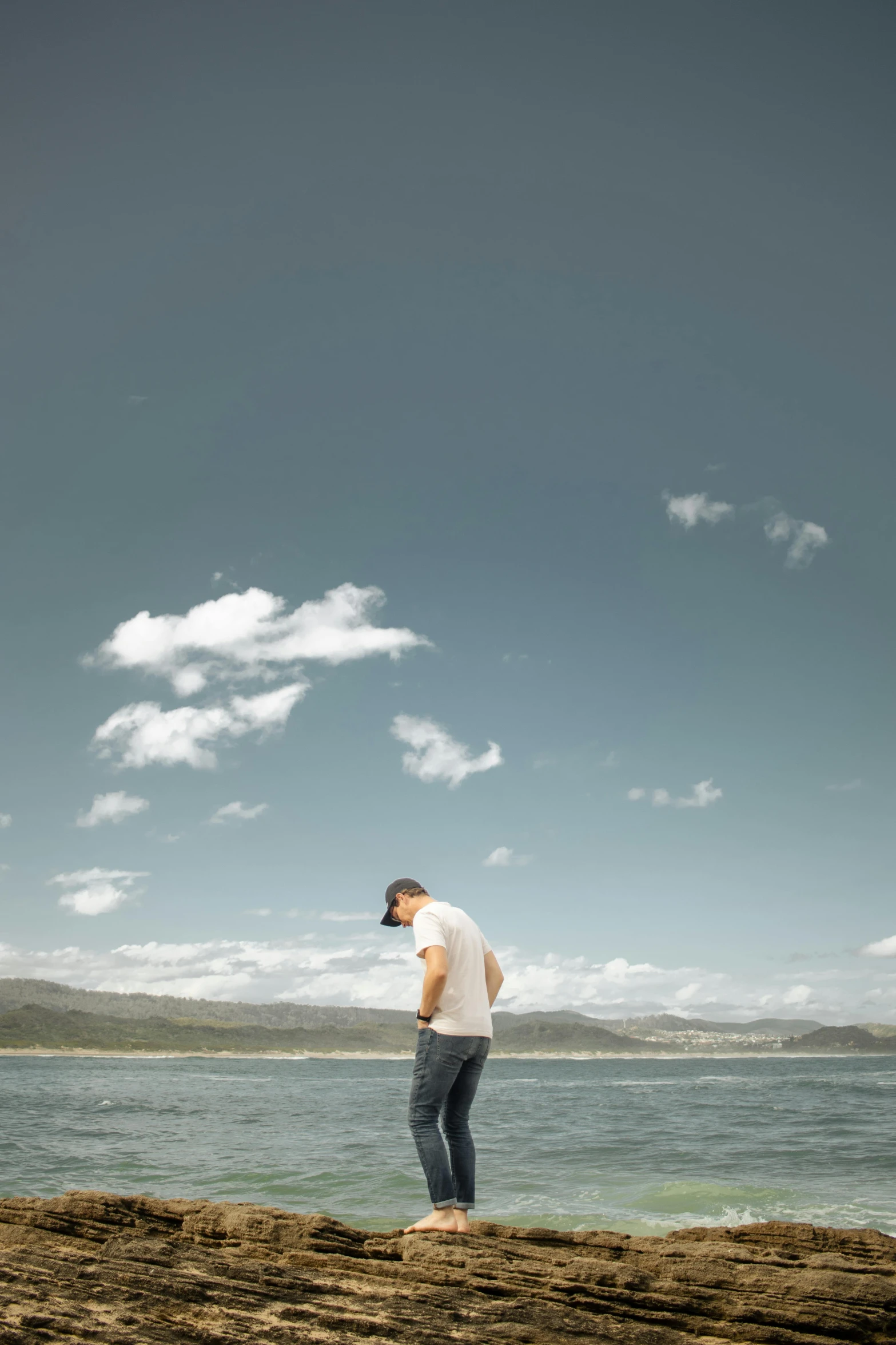 man standing on sand next to the ocean