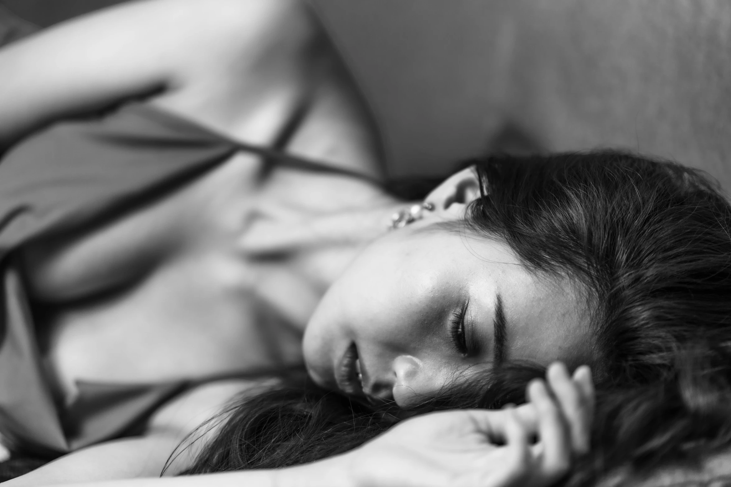 woman with long dark hair is laying down on her side on a bed