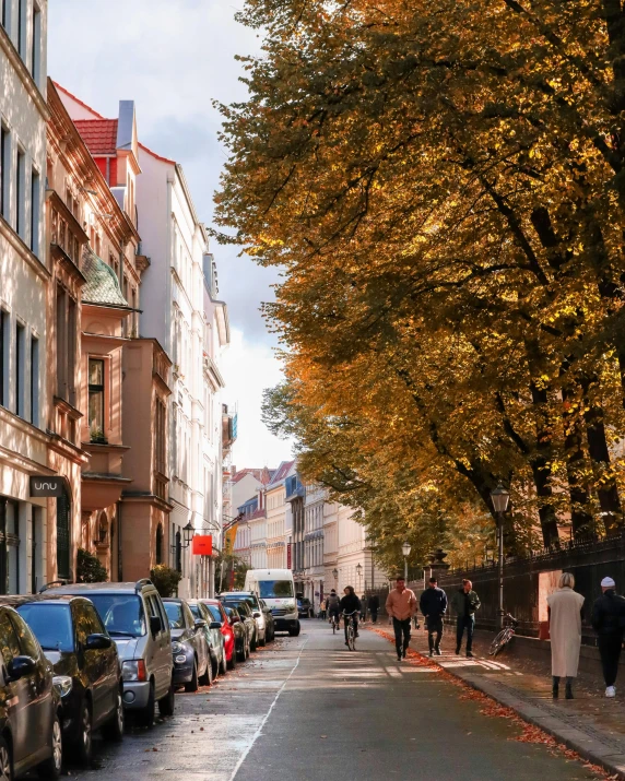 a long road lined with parked cars and people walking down one