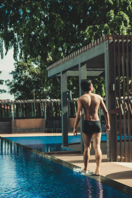 a young man stands beside the edge of a pool