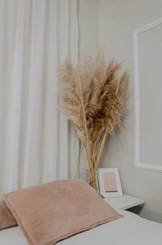 a white bed with pink pillows and a small plant