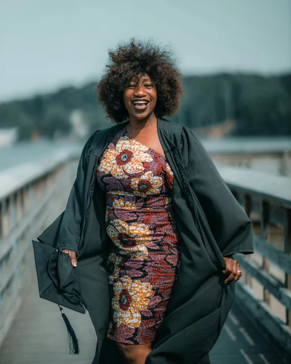 a woman with afro hair wearing a coat smiling