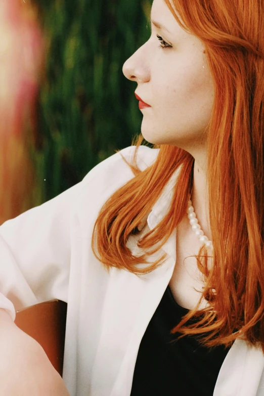 a woman with long red hair standing next to a tree