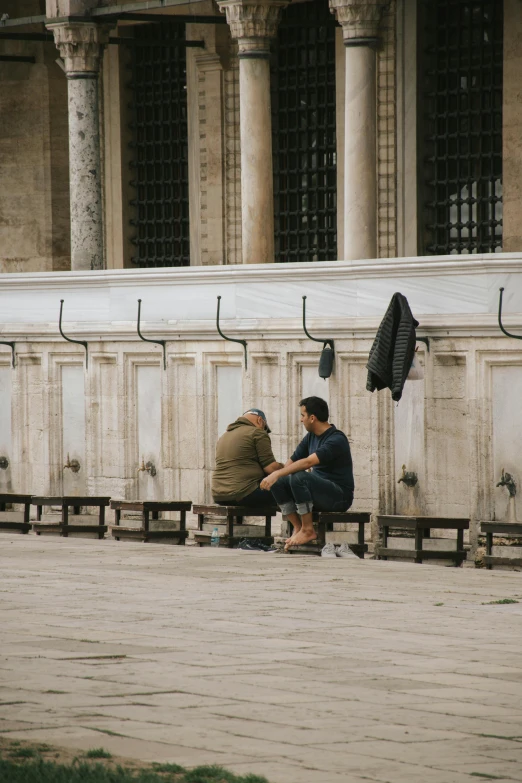 a man sitting on a cement bench with an umbrella