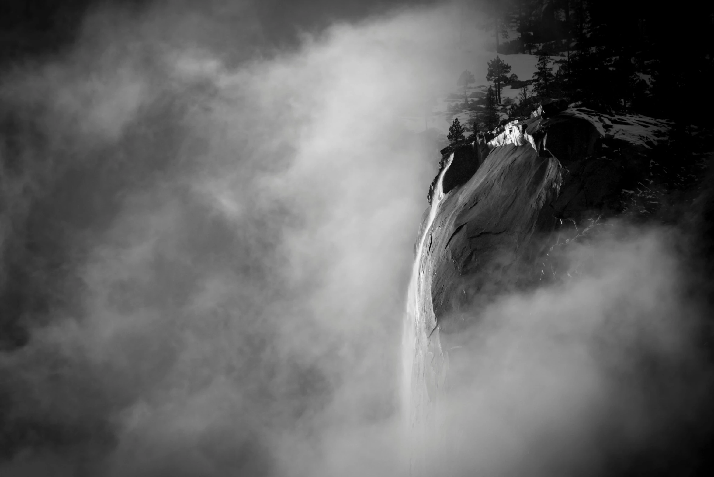 a person is standing on the edge of a cliff while clouds are covering them