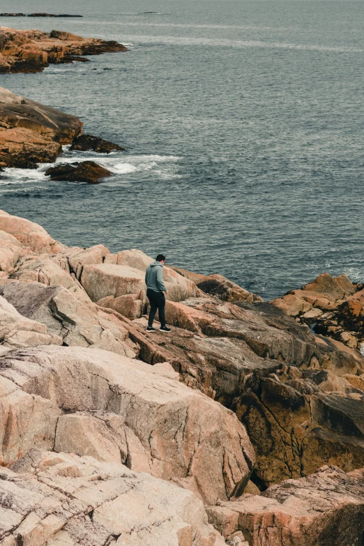 man standing at the top of large rocks near ocean