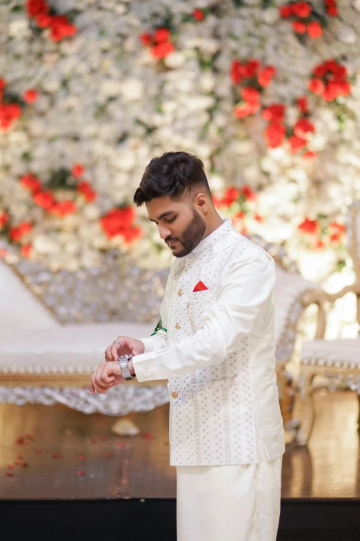 a man in a white suit and flowered wall