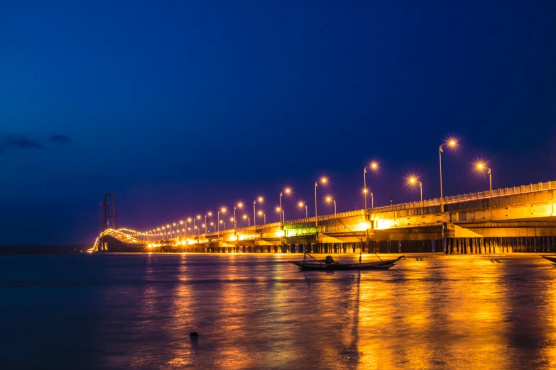 a city bridge over the ocean at night