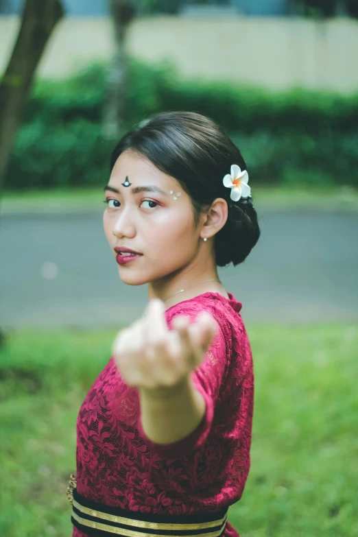 a young woman in traditional asian garb pointing at soing