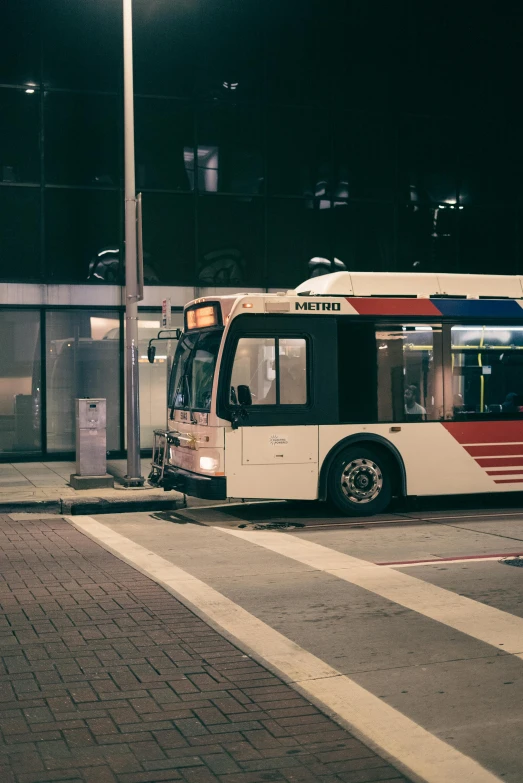 an empty public transit bus on the side of the road at night