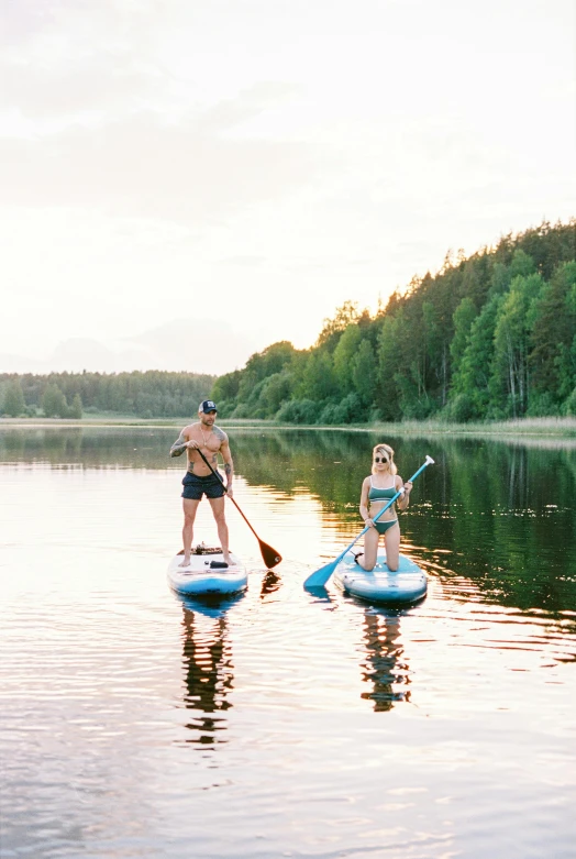 two people paddle boarding on a calm lake