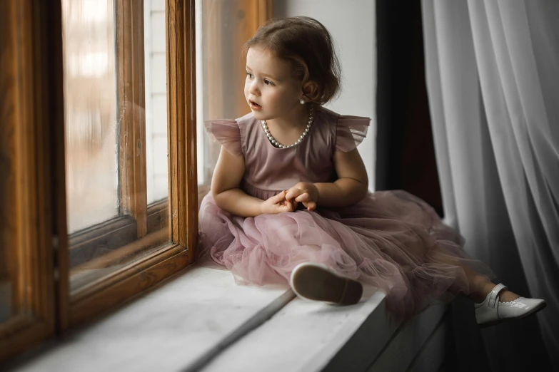 an adorable little girl looking out a window