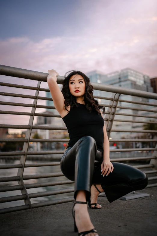 a beautiful woman sitting on the edge of a fence