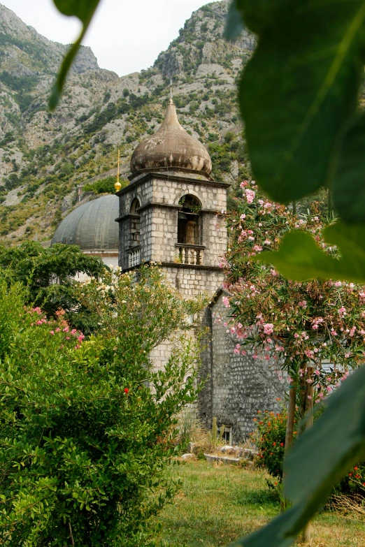 a old building with a bell tower surrounded by trees and bushes