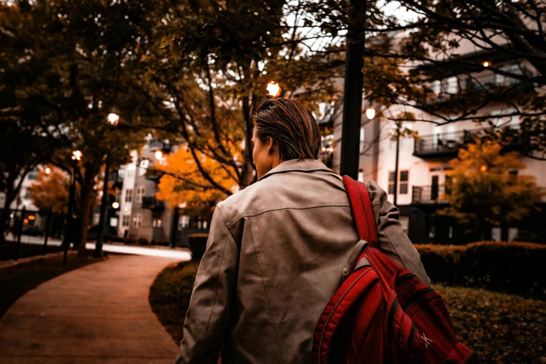 the back of a person with a backpack on and a street light in the background