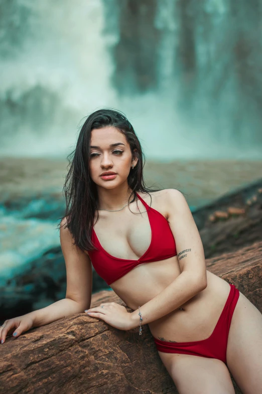 a beautiful woman in red bikini next to a waterfall