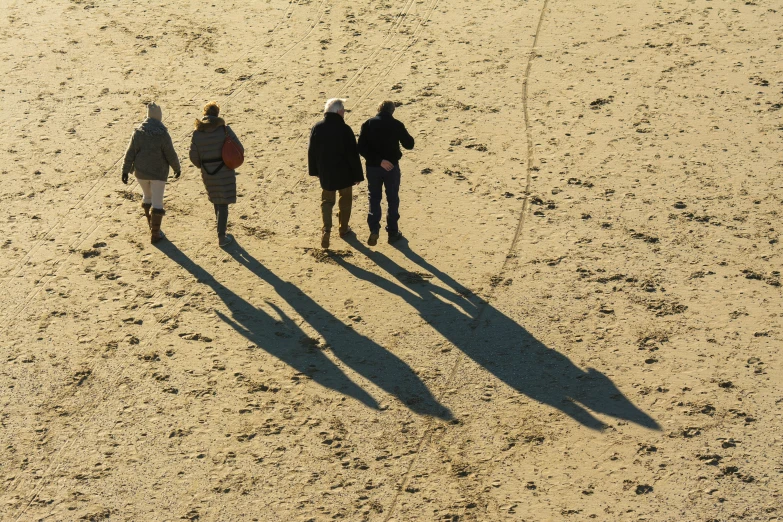 a couple of people walking in the sand