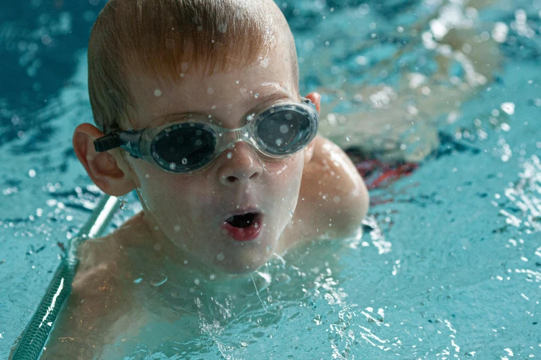 a young child wearing goggles swimming in a pool