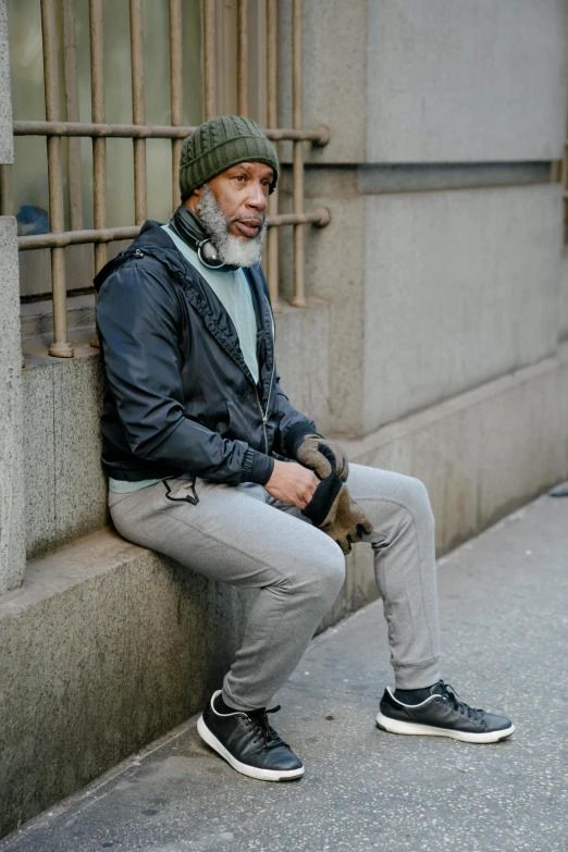 an old man sitting by some concrete wall