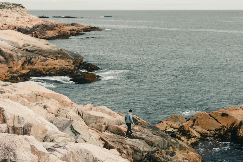 a man stands on rocks by the water