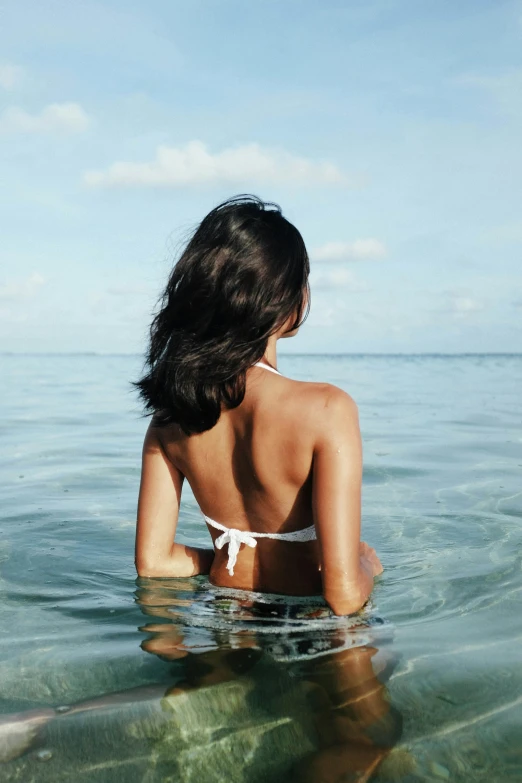 woman sitting in the ocean staring out into the ocean