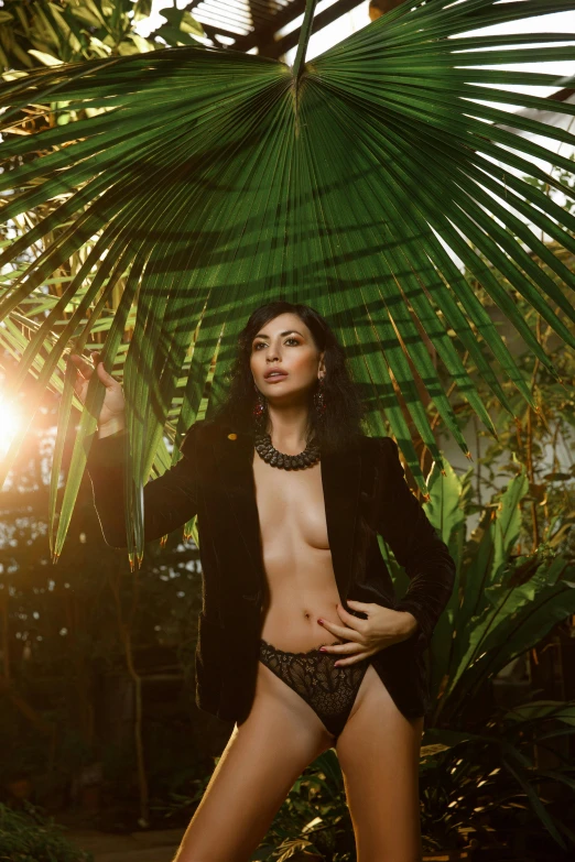 a  woman in black lingerie standing next to a palm tree