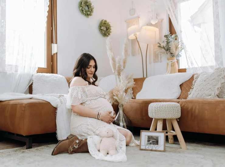 the pregnant woman is sitting on her couch in front of her family portraits