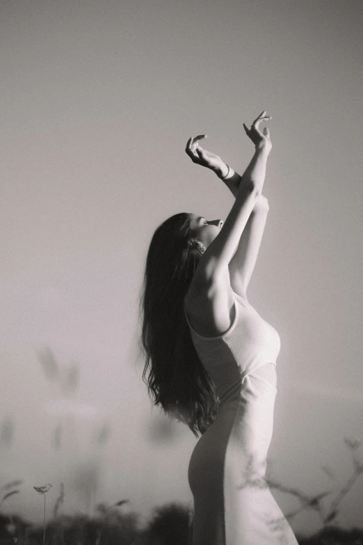 a woman reaching up towards the sky, with her arms up