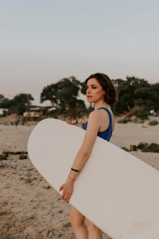 a woman in a blue dress carrying a surf board