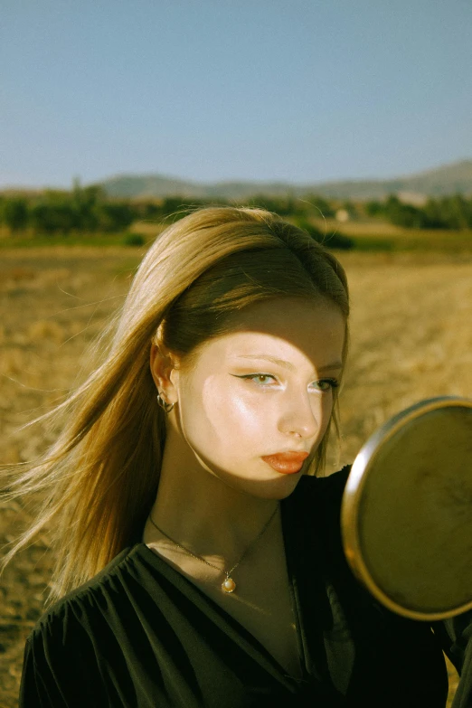 a woman holding a mirror looking into the distance