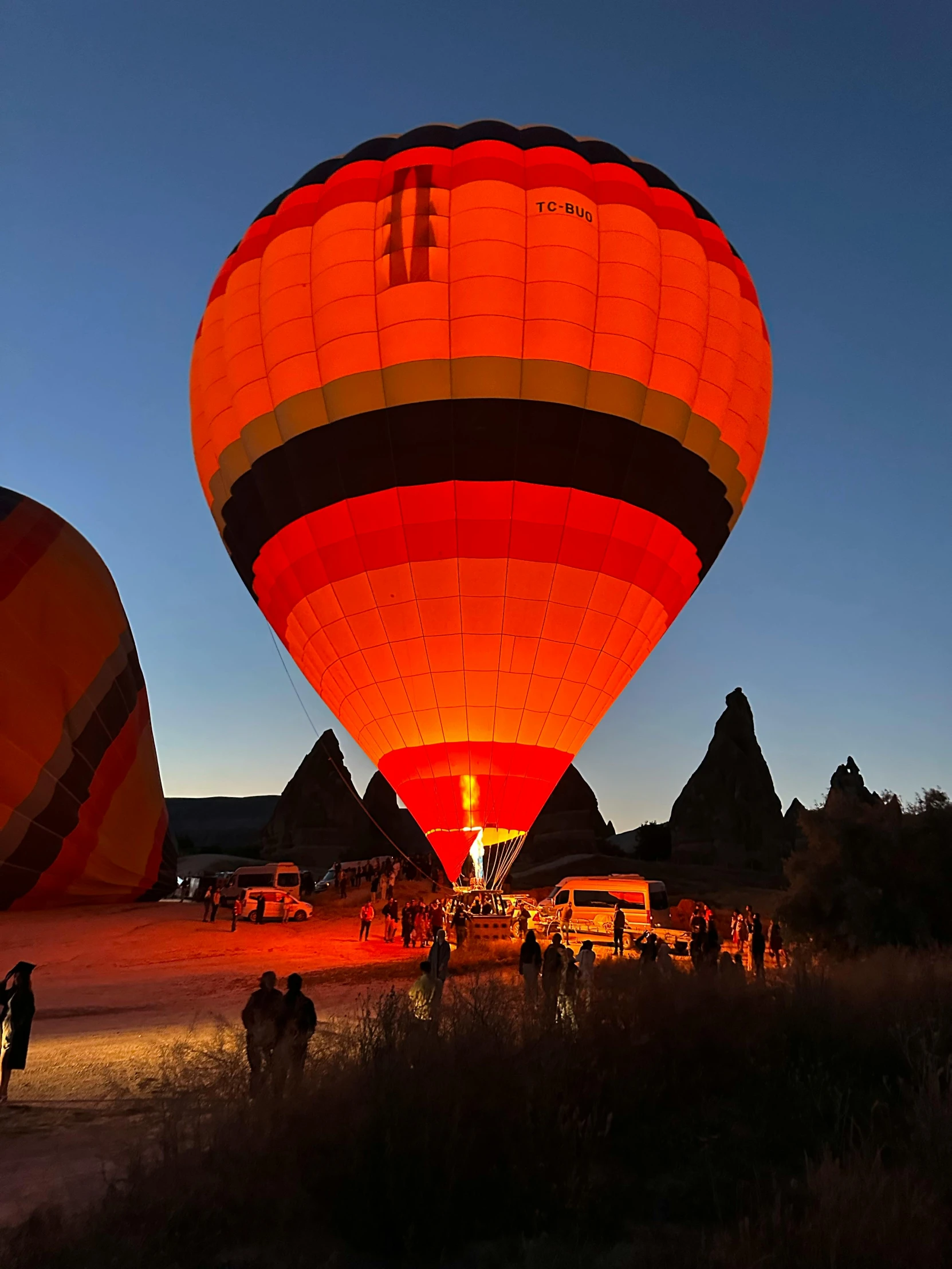 two  air balloons lit up at night with some people in the background