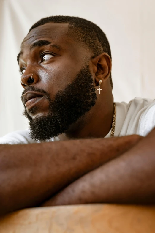 a man sitting down and wearing gold cross earrings