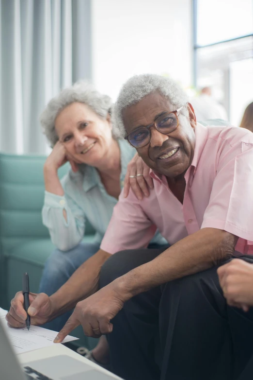 an older man and woman looking at a laptop